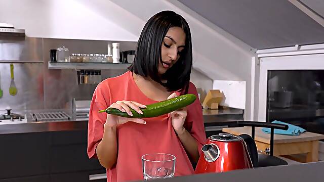 A cute girl peels a cucumber for her older man in a sensual scene.